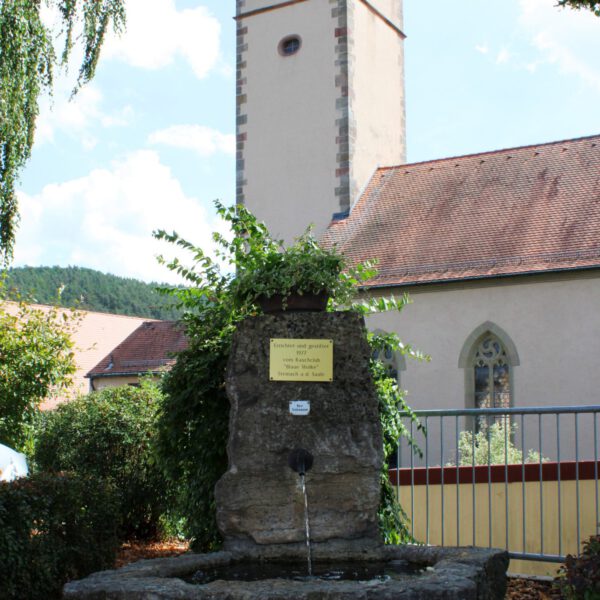 Brunnen mit Blick auf die Katholische Pfarrkirche St. Nikolaus in Steinach
