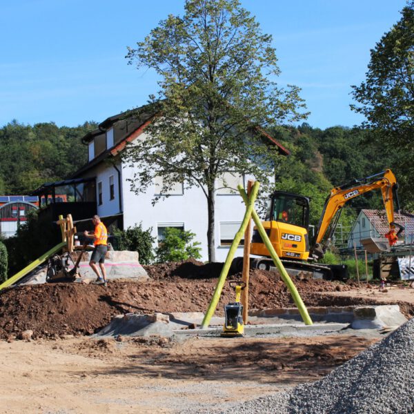 Bauhofmitarbeiter begradigen die Erde um das Spielgerät